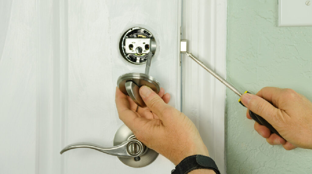 A locksmith repairing a door lock to enhance home security