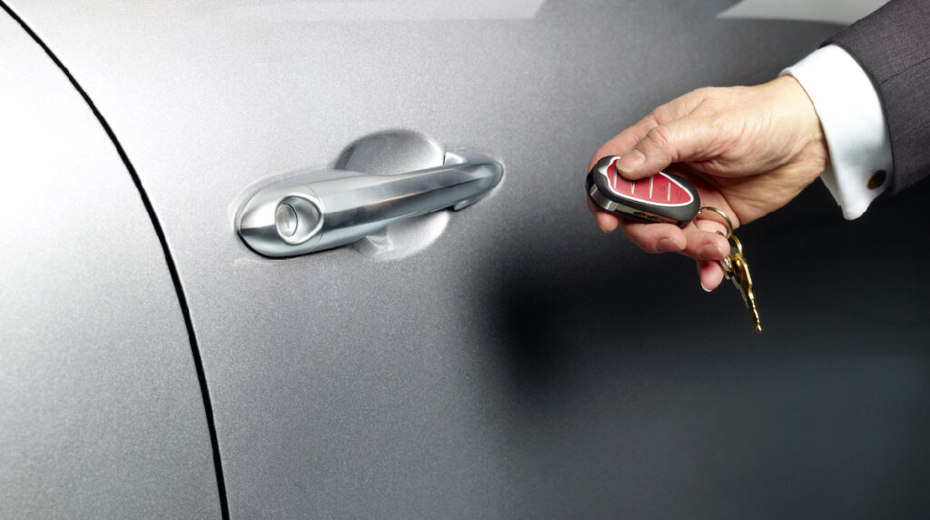 A locksmith using advanced technology to program a car key fob, enhancing vehicle security in Abu Dhabi.